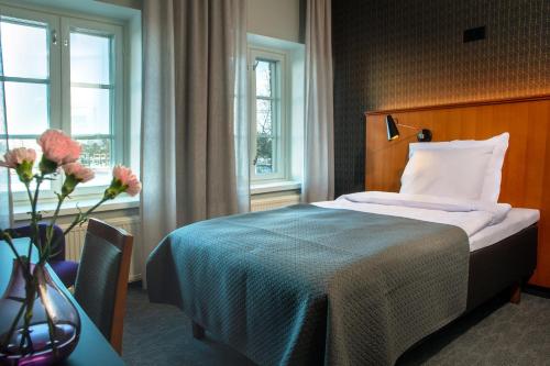 a hotel room with a bed and a table and windows at Hotel Lasaretti in Oulu