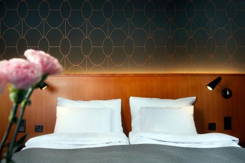 a bed with white pillows and a wooden headboard at Hotel Lasaretti in Oulu