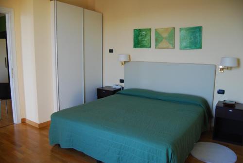 a bedroom with a bed with a green bedspread at Hotel Residence La Luna Nel Porto in Stresa