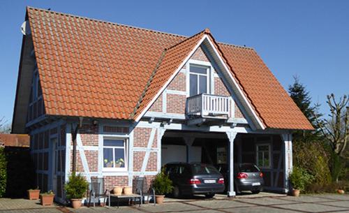 ein Haus mit zwei Autos, die davor geparkt sind in der Unterkunft Casa Carina Ferienhaus, Oberwohnung mit kleinem Sonnenbalkon und Terrasse in Süderschweiburg
