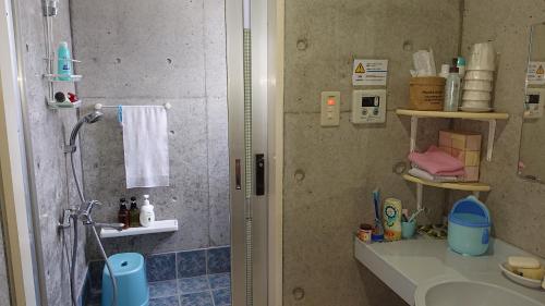 a bathroom with a shower and a sink and a shower at Guesthouse Seaglass in Itoman
