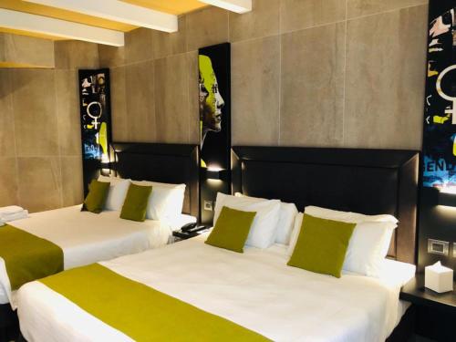 two beds in a hotel room with green and white pillows at Just Hotel Milano in Milan