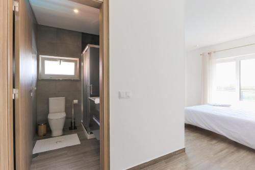 a bathroom with a toilet and a bed in a room at Vitamin Sea, The Sea View Apartment in Baleal
