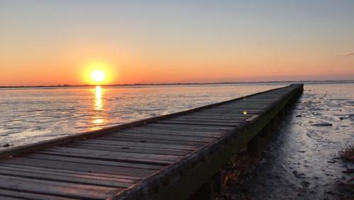 a dock in the water with the sunset in the background at Ferienwohnung An Bord in Dangast
