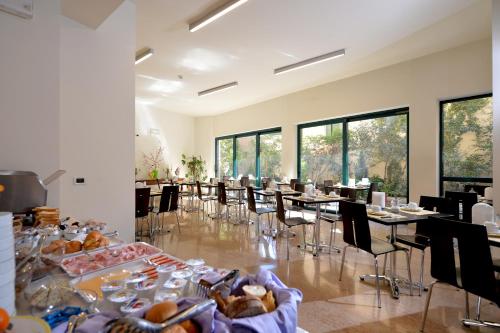 uma sala de jantar com mesas, cadeiras e janelas em Hotel Siena em Verona