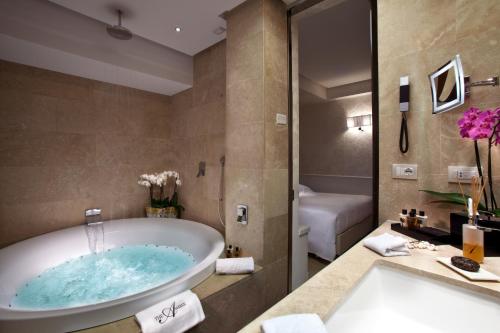 a bathroom with a tub and a toilet and a sink at The Ashbee Hotel in Taormina