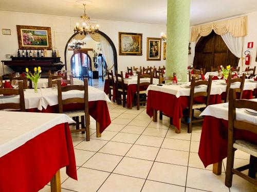 a restaurant with tables and chairs with red table cloth at Hotel Villaggio Ristorante Pizzeria Museo TANIT in Carbonia
