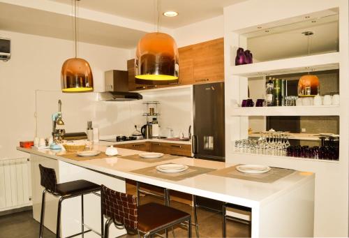 a kitchen with a large white counter with chairs at Tbilisi View Hotel in Tbilisi City
