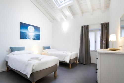 a white room with two beds and a window at CASA PERLASCA in Cernobbio