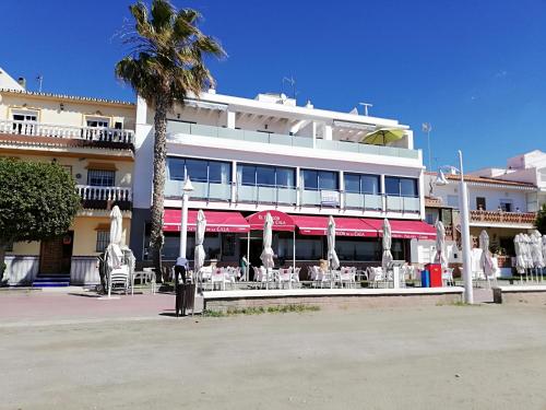 a hotel with tables and umbrellas in front of a building at Apartamentos Varadero Sea View in Cala del Moral