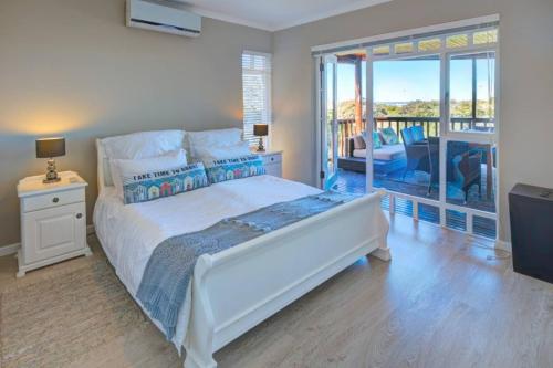 a bedroom with a large white bed and a balcony at Wilderness Views Self Catering Apartment in Wilderness