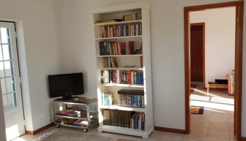 ein Bücherregal voller Bücher und Fernseher in der Unterkunft Casa Harmonica com vista mar in Areia Branca