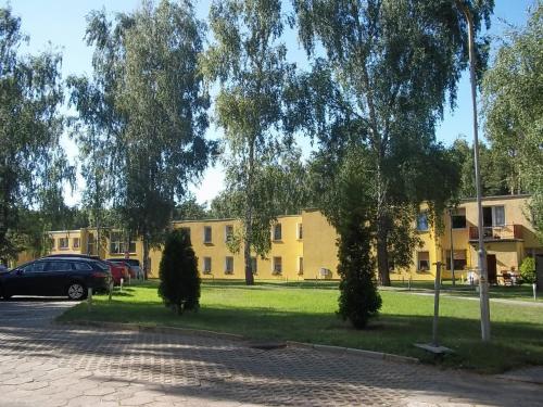 a building with cars parked in a park with trees at Fala1 Ośrodek Wypoczynkowy in Gdańsk