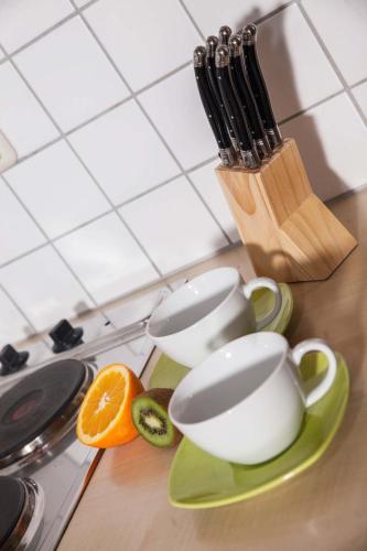 a counter with three cups and an orange on a cutting board at Ferienhaus Butterfly in Garmisch-Partenkirchen