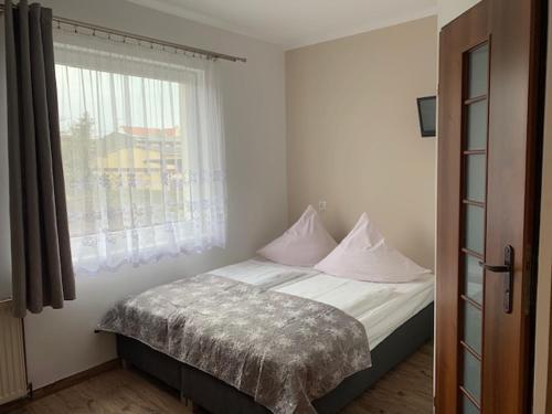 a bedroom with a bed with white sheets and a window at Willa Solna in Kołobrzeg