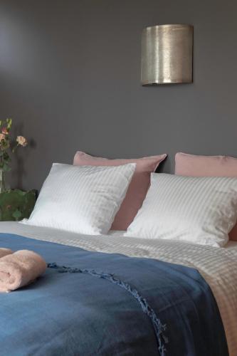 a bed with white and pink pillows on it at Beeltjens B&B: Wolf&Belle in Westerlo