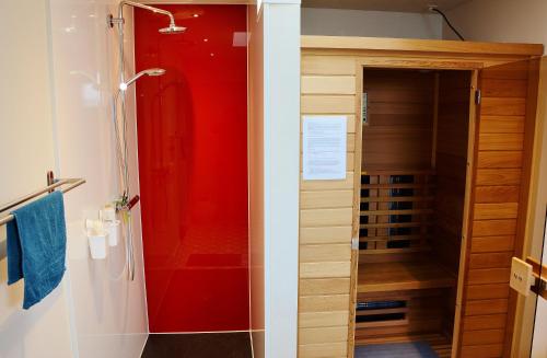 a bathroom with a shower with a red wall at Beeltjens B&B: Wolf&Belle in Westerlo