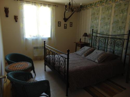 a bedroom with a bed and two chairs at LA MARVINIERE in Saint-Bonnet-sur-Gironde