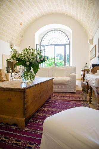 a living room with a table with a vase of flowers at Masseria Montelauro in Otranto