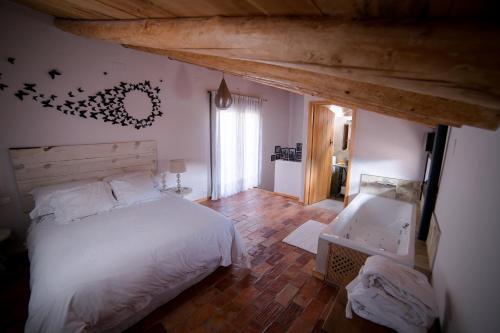 um quarto com uma cama branca e um tecto de madeira em El Zaguán em Albarracín