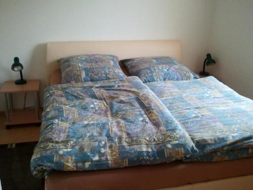 a bed with a comforter and pillows on it at Ferienwohnung Sonne-Stadtrand Dresden in Moritzburg
