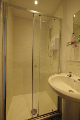 a shower with a glass door next to a sink at The Sandhill in Sandown