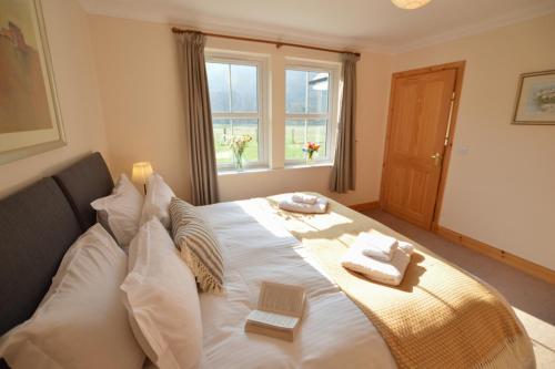 a bedroom with a large white bed with pillows at Feochan Bheag in Oban