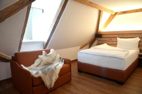 a bedroom with a bed and a chair in a room at Am Zehntstadl Hotel & Sauna in Ulm