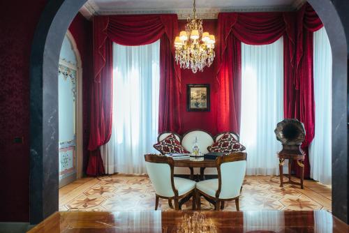 a dining room with red curtains and a table and chairs at Relais & Chateaux Villa Crespi in Orta San Giulio