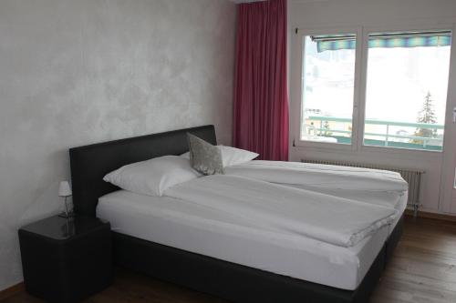 um quarto com uma cama branca e uma janela em Bernina Bed and Breakfast em Davos