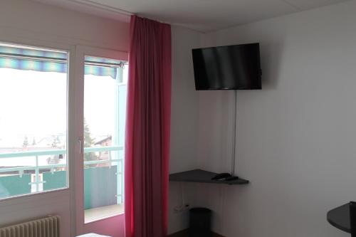 Cette chambre comprend une télévision et un rideau rouge. dans l'établissement Bernina Bed and Breakfast, à Davos