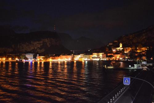 a city lit up at night on the water at Hotel Paradiso Conca d'Oro in Nago-Torbole