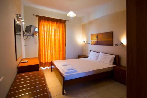 1 dormitorio con 1 cama con cortina amarilla y ventana en Vakis apartments, en Zacharo