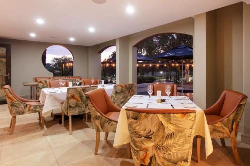 a dining room with tables and chairs and windows at The Rasmus in Pretoria