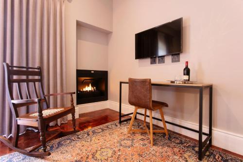 a living room with a table and a chair and a fireplace at The Rasmus in Pretoria