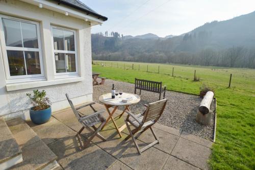 a table and chairs on a patio with a view of a field at Feochan Bheag in Oban
