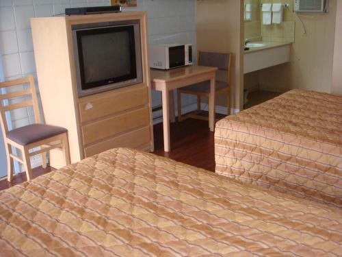 a hotel room with a tv and a bed and a desk at Trans Canada Motel in Kamloops