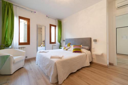 a bedroom with a large bed and a chair at Serenissima Apartments in Venice