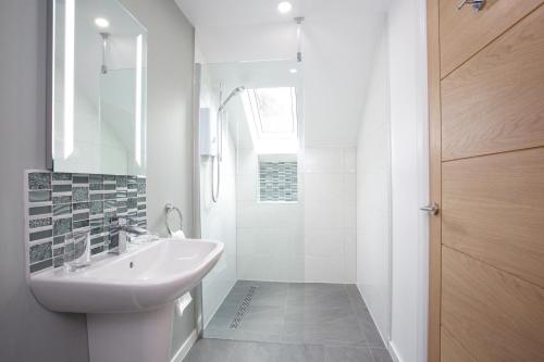 y baño blanco con lavabo y ducha. en Dunmurray Lodge Guesthouse and Loft Apartment, en Pitlochry