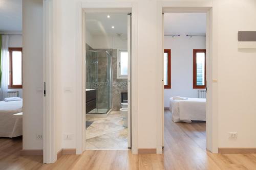 un baño con una puerta de cristal que conduce a un dormitorio en Serenissima Apartments, en Venecia