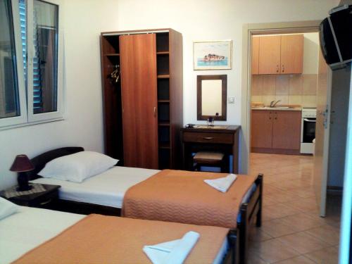 a room with two beds and a desk with a mirror at Oaza Guest House in Sveti Stefan