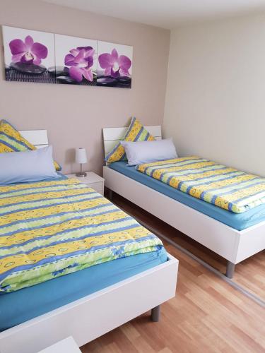 - 2 lits dans une chambre avec des fleurs violettes sur le mur dans l'établissement Haus Ella, à Hombourg