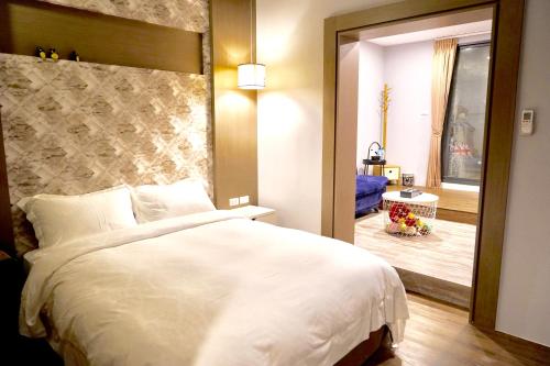 a bedroom with a large white bed and a mirror at MTNY Hotel in Zhushan