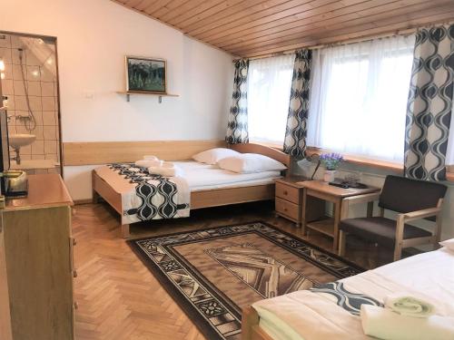 a bedroom with two beds and a desk and a window at Pensjonat Adria in Zakopane