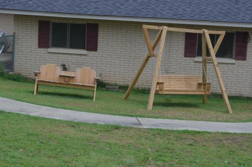 two benches sitting in the grass in front of a house at Ouachita Mountain Inn in Glenwood