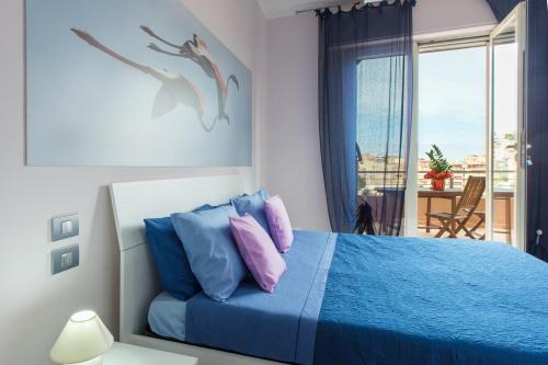 Un dormitorio con una cama azul con almohadas azules y rosas en A View on Cagliari en Cagliari