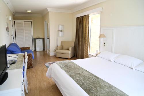 a hotel room with a bed and a living room at Vitória Hotel Convention Indaiatuba in Indaiatuba