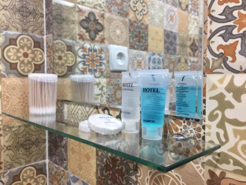 a glass shelf with products on it in a bathroom at Guest House Maradona in Sighnaghi