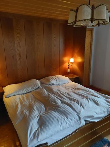 an unmade bed in a bedroom with a wooden wall at Pension Eder - Joker card included in summer in Saalbach Hinterglemm