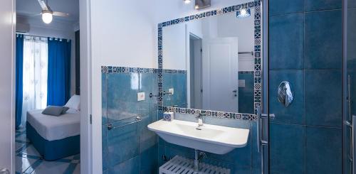 Un baño azul con lavabo y espejo. en B&B Amalfè, en Maiori